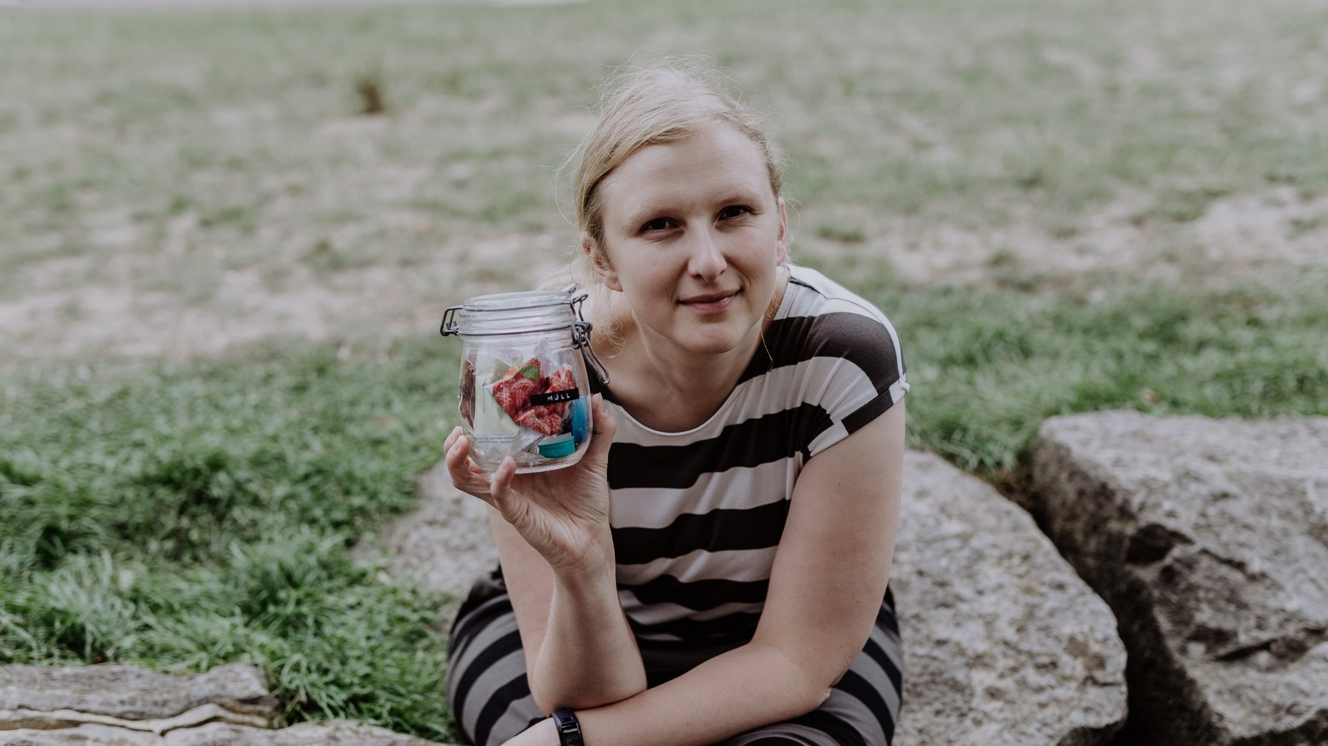Amelie hält ein Glas mit Müll