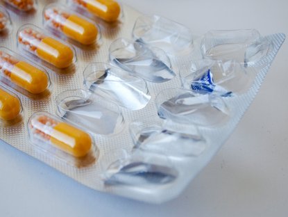 Angefangene Pillenverpackung mit orange-gelben Pillen