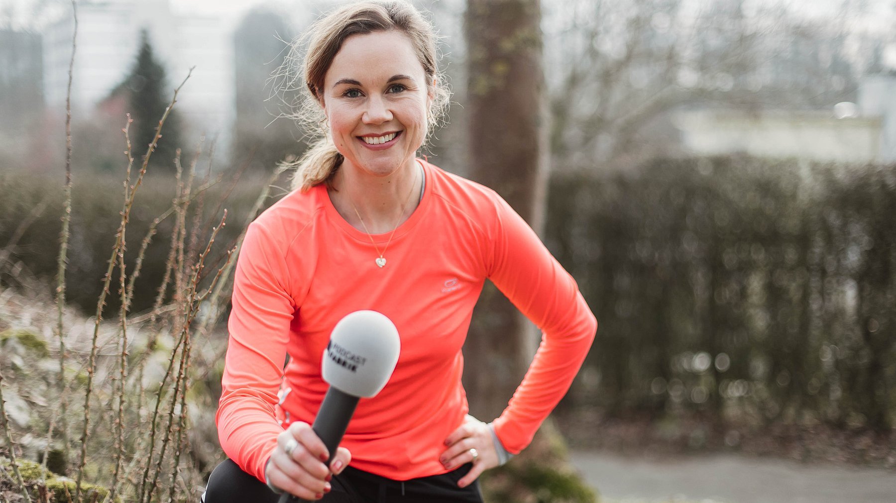 Julia Ures mit dem Mikro der Podcastfabrik in Sportkleidung