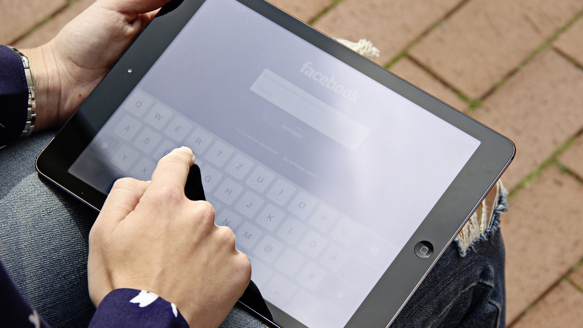 Person meldet sich über ein iPad bei Facebook an